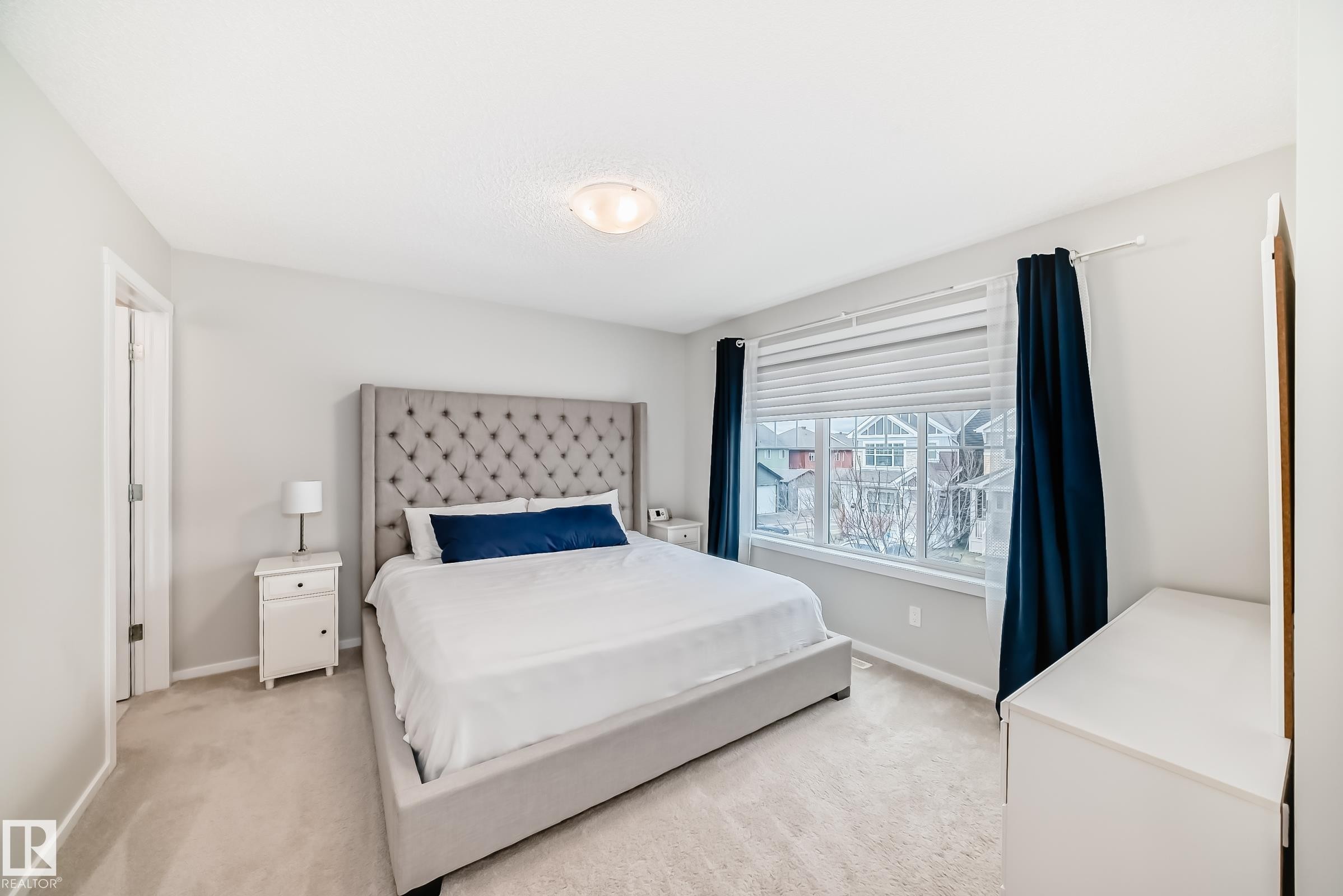 Carpeted bedroom featuring a large window, neutral wall paint, and a built-in overhead light fixture - 3278 Cherry Crescent, Edmonton, AB - Indoor Photo Showing Bedroom