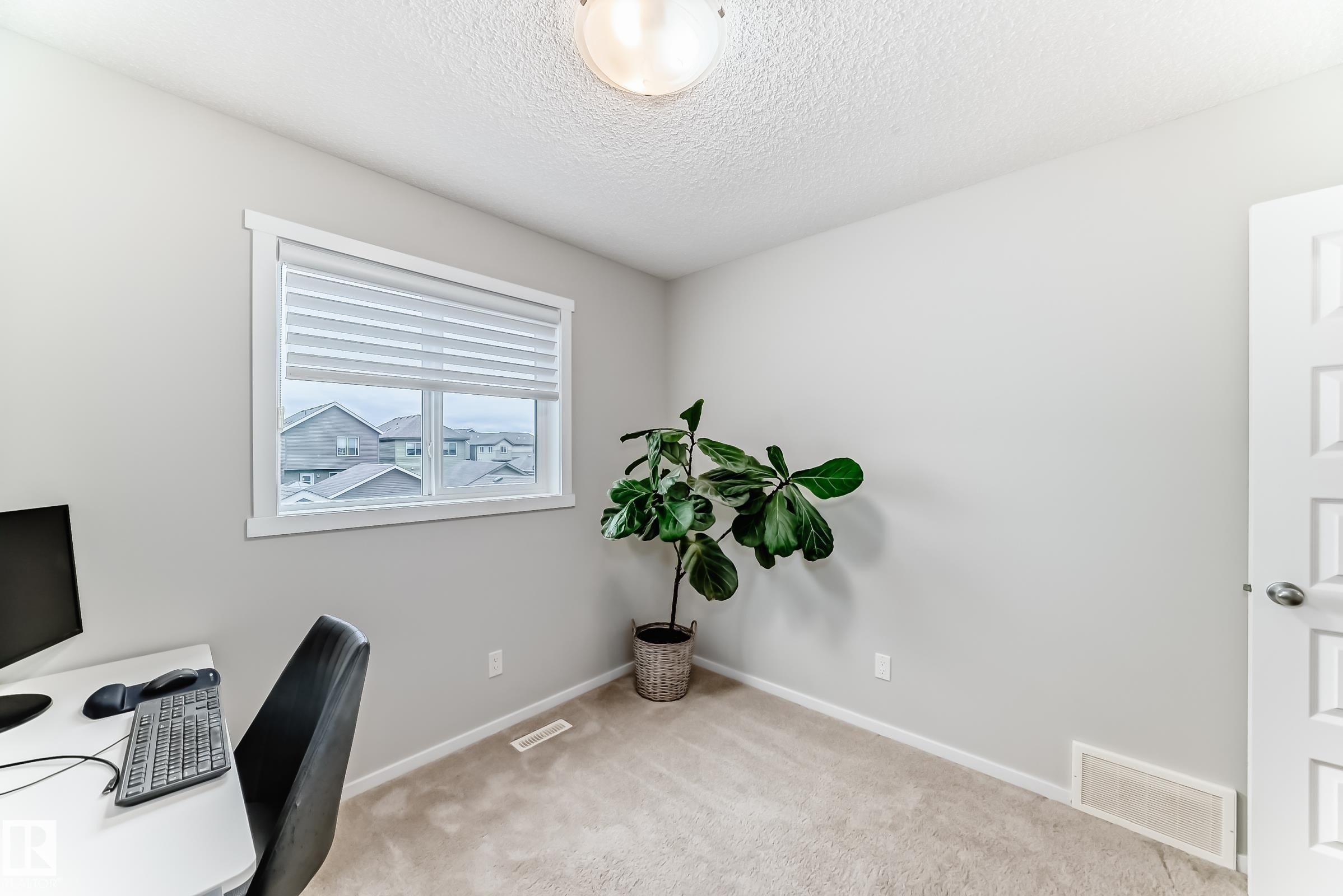 Windowed interior space featuring light beige carpeting, neutral wall paint, white baseboards, and a white paneled door - 3278 Cherry Crescent, Edmonton, AB - Indoor Photo Showing Office