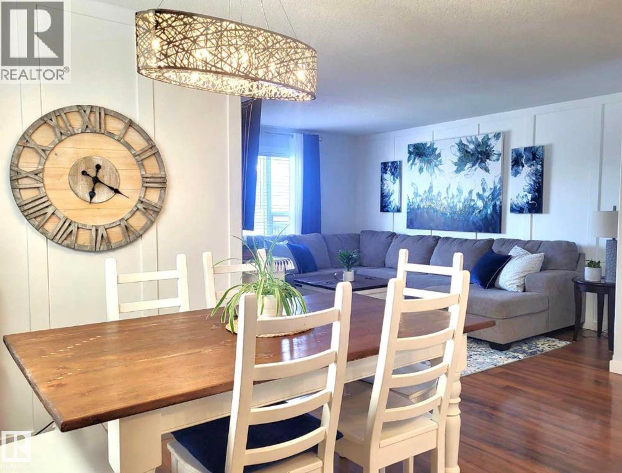 Dining area featuring a wood-finish table, white painted chairs, and a modern chandelier - 144 Kirpatrick Way, Leduc, AB - Indoor Photo Showing Dining Room