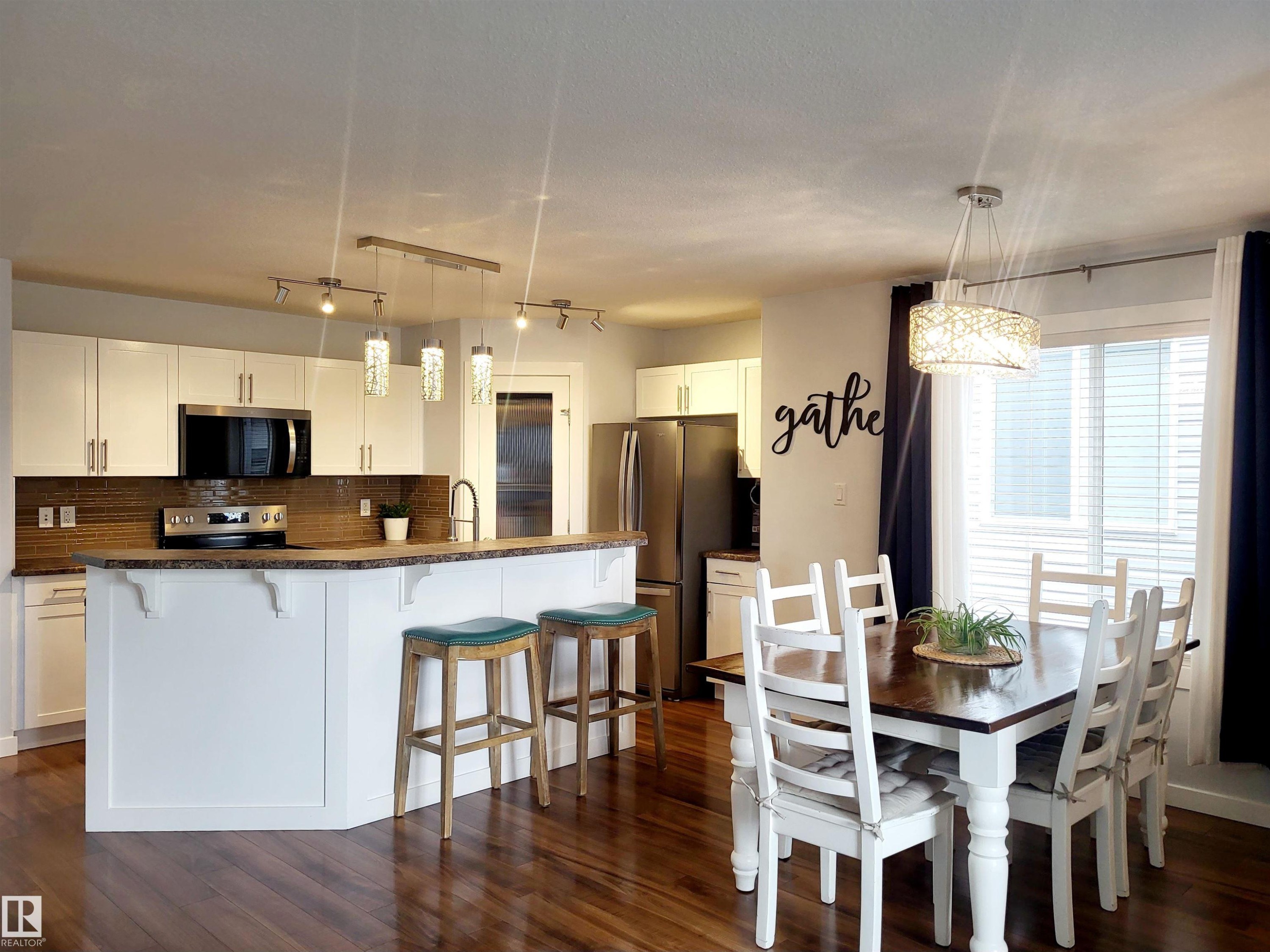 Open-concept kitchen and dining area featuring rich wood-finish flooring - 144 Kirpatrick Way, Leduc, AB - Indoor
