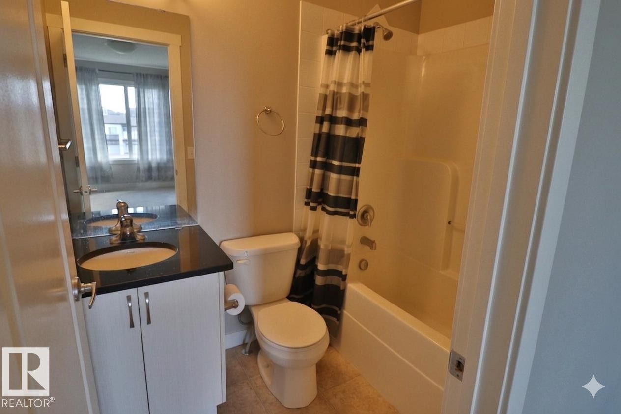 Bathroom featuring a single vanity with a dark countertop, white cabinetry, and a mirrored medicine cabinet - 81 446 Allard Blvd, Edmonton, AB - Indoor Photo Showing Bathroom