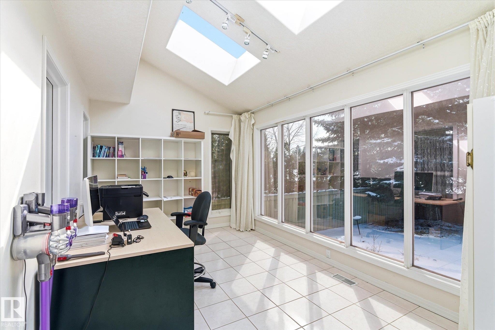 This bright room features a vaulted ceiling with two skylights, track lighting, and tiled flooring - 128 Weaver Drive, Edmonton, AB - Indoor Photo Showing Office