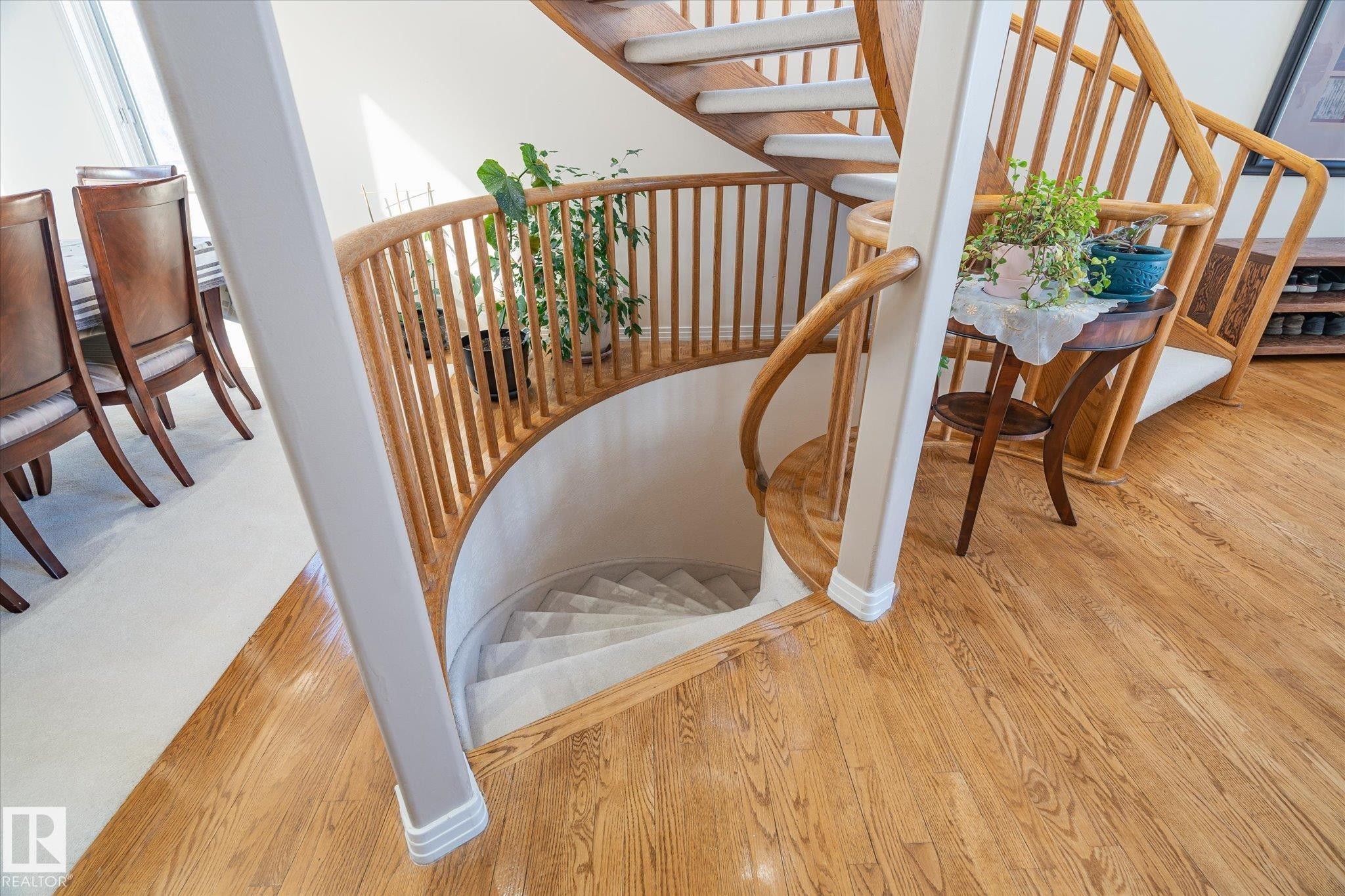 The property features a spiral staircase with light wood railings and carpeted treads, complemented by hardwood flooring in the surrounding area - 128 Weaver Drive, Edmonton, AB - Indoor Photo Showing Other Room