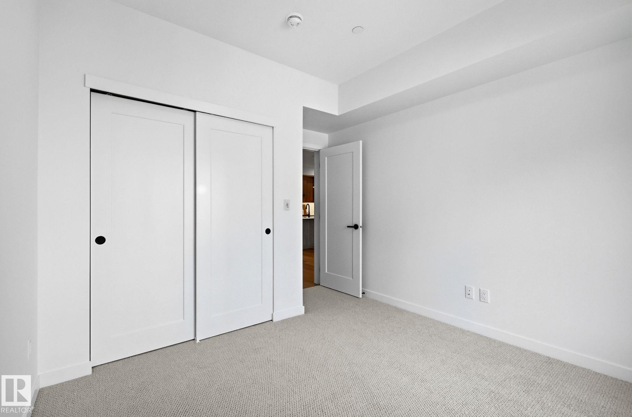 Neutral-toned carpet flooring complementing white walls and trim - 202 7459 May Common, Edmonton, AB - Indoor Photo Showing Other Room