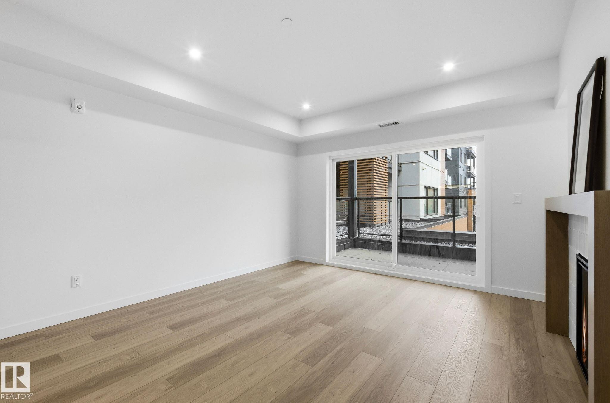 Light wood-finish flooring complements the white walls and recessed lighting - 202 7459 May Common, Edmonton, AB - Indoor Photo Showing Other Room
