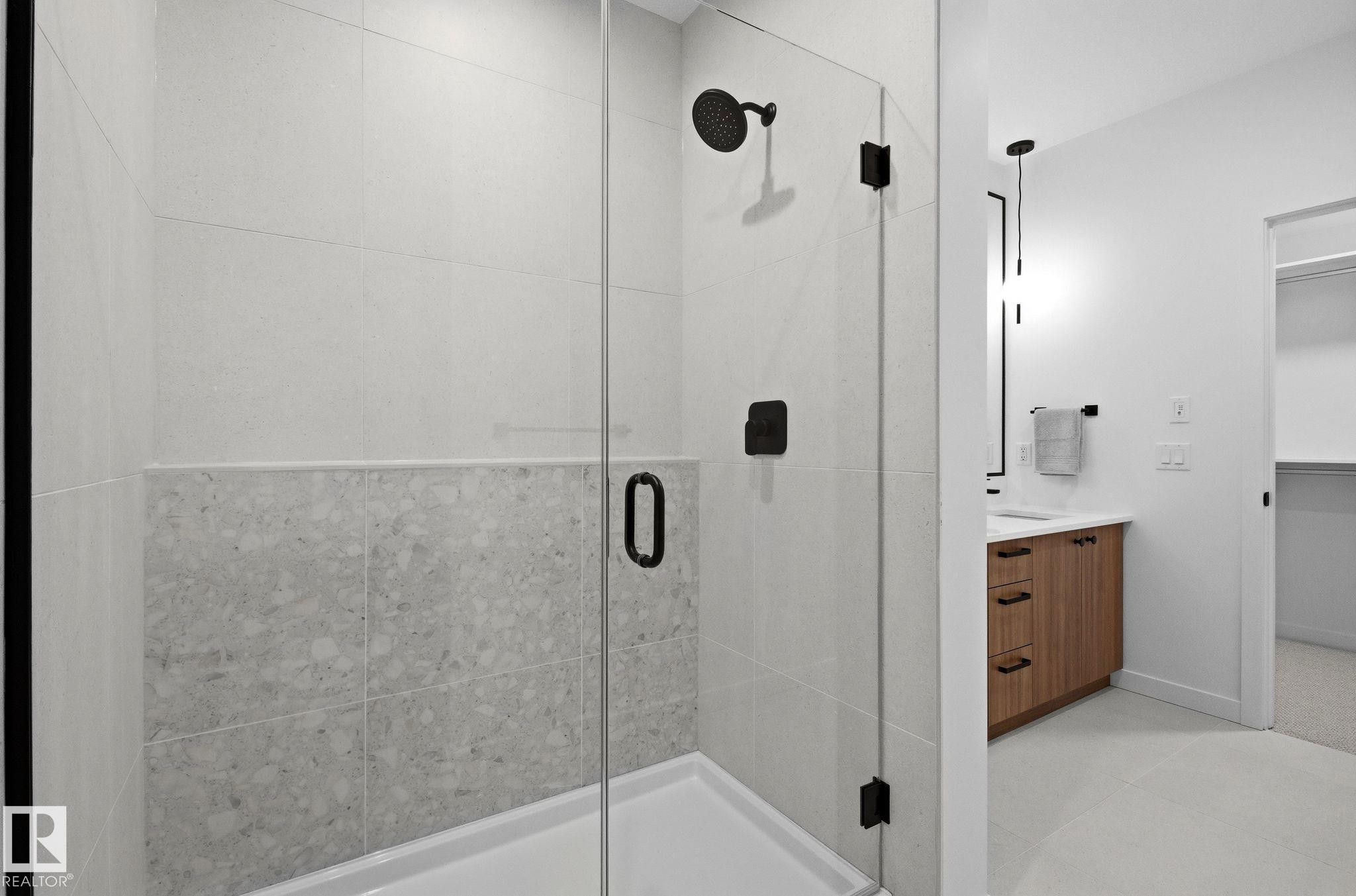 Glass-enclosed shower with matte black fixtures and a tiled surround - 202 7459 May Common, Edmonton, AB - Indoor Photo Showing Bathroom