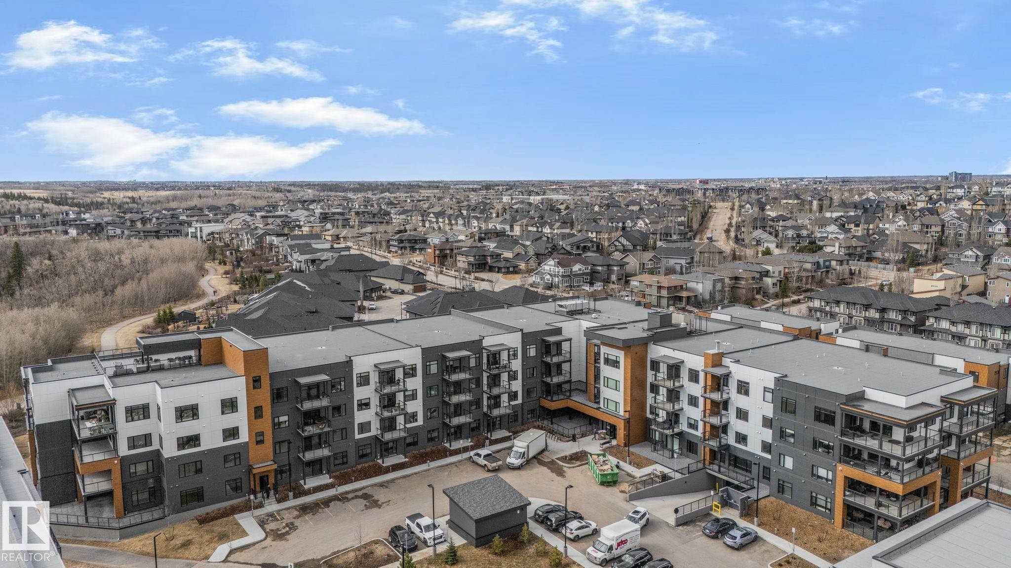 Multi-story residential building featuring a contemporary design with grey, white, and wood-toned paneling - 202 7459 May Common, Edmonton, AB - Outdoor With View