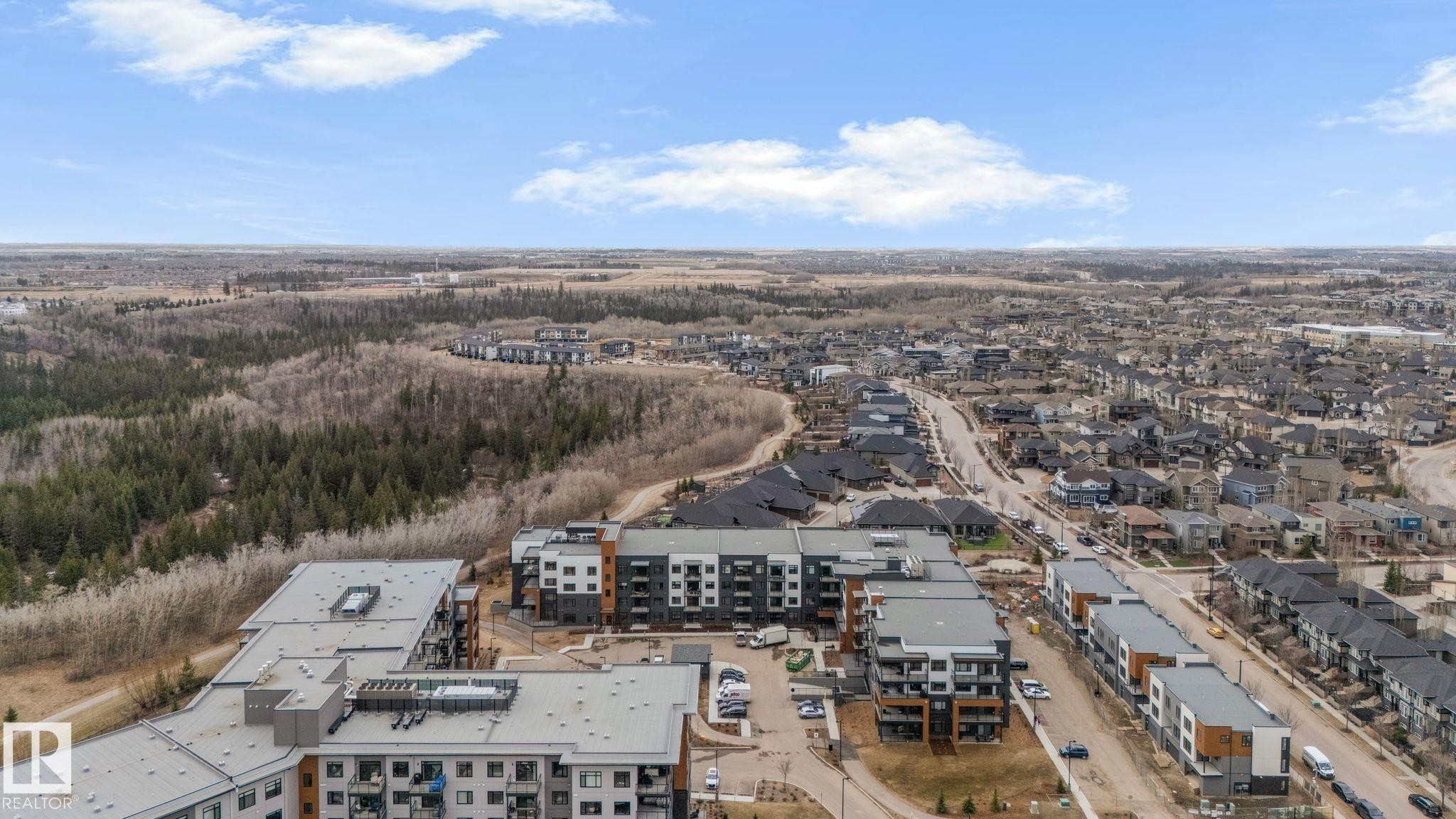 Aerial perspective showcasing a developing residential area with a mix of multi-story buildings and single-family homes - 202 7459 May Common, Edmonton, AB - Outdoor With View