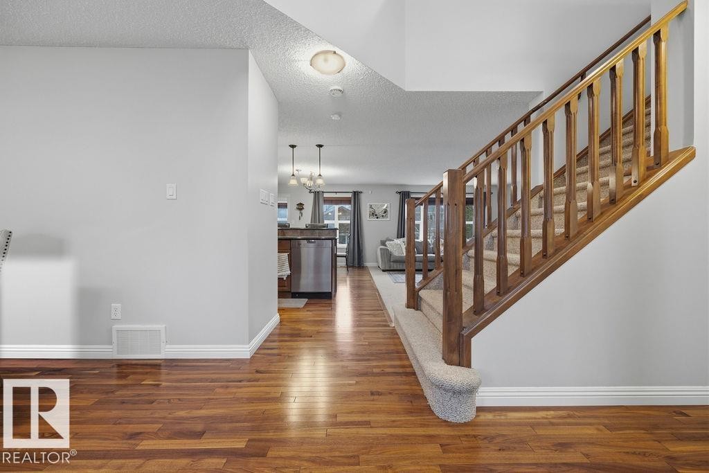 Warm wood-finish flooring extending from the entryway - 1613 Kerr Road, Edmonton, AB - Indoor Photo Showing Other Room