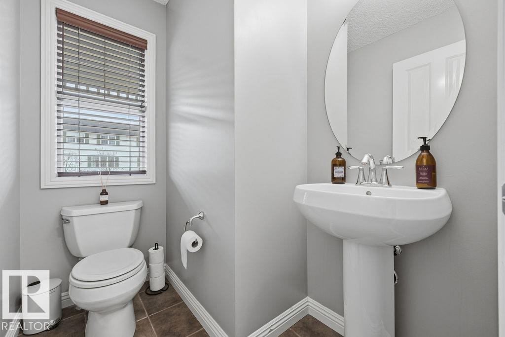 Pedestal sink with an oval mirror, chrome faucet, and tile flooring - 1613 Kerr Road, Edmonton, AB - Indoor Photo Showing Bathroom