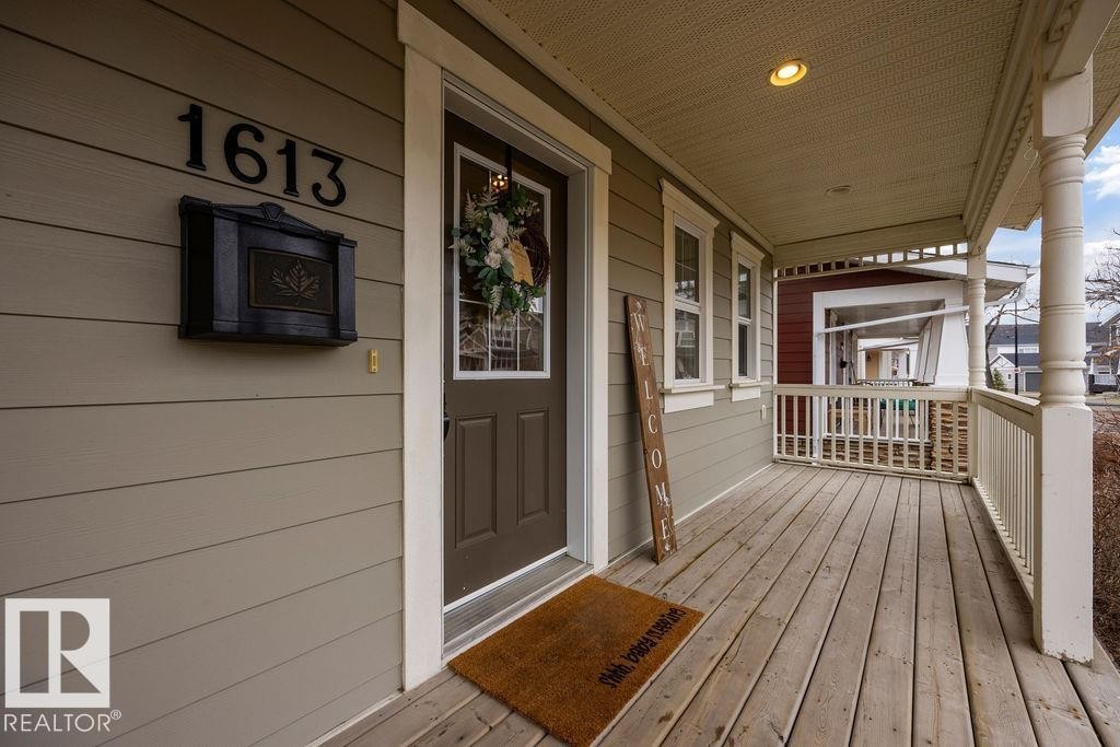 Expansive covered front porch featuring wood plank flooring and a decorative railing - 1613 Kerr Road, Edmonton, AB - Outdoor With Deck Patio Veranda With Exterior