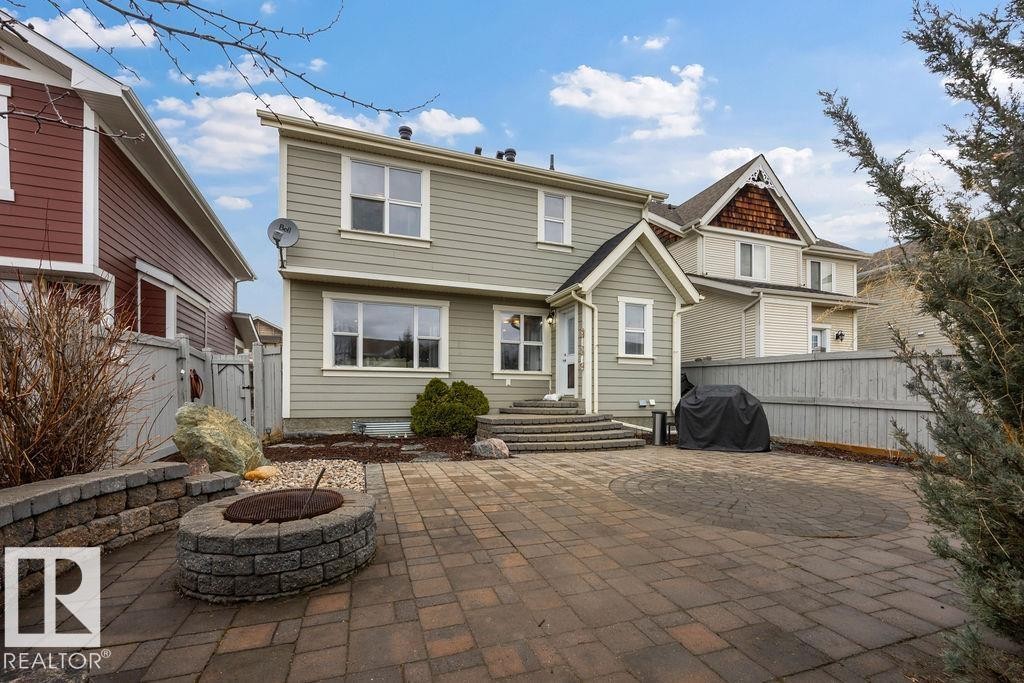 Expansive backyard featuring a brick paver patio, a built-in stone fire pit, and a stone retaining wall - 1613 Kerr Road, Edmonton, AB - Outdoor With Facade
