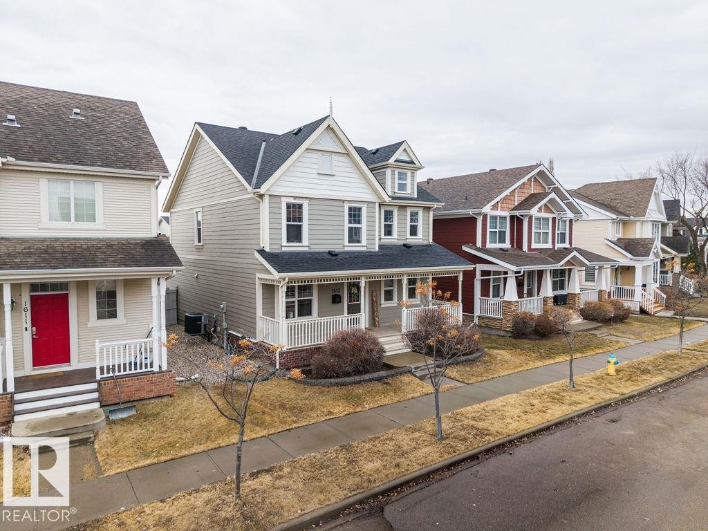 Contemporary facade featuring light grey siding, white trim, a covered front porch with white railing, and a gabled roofline - 1613 Kerr Road, Edmonton, AB - Outdoor With Deck Patio Veranda With Facade