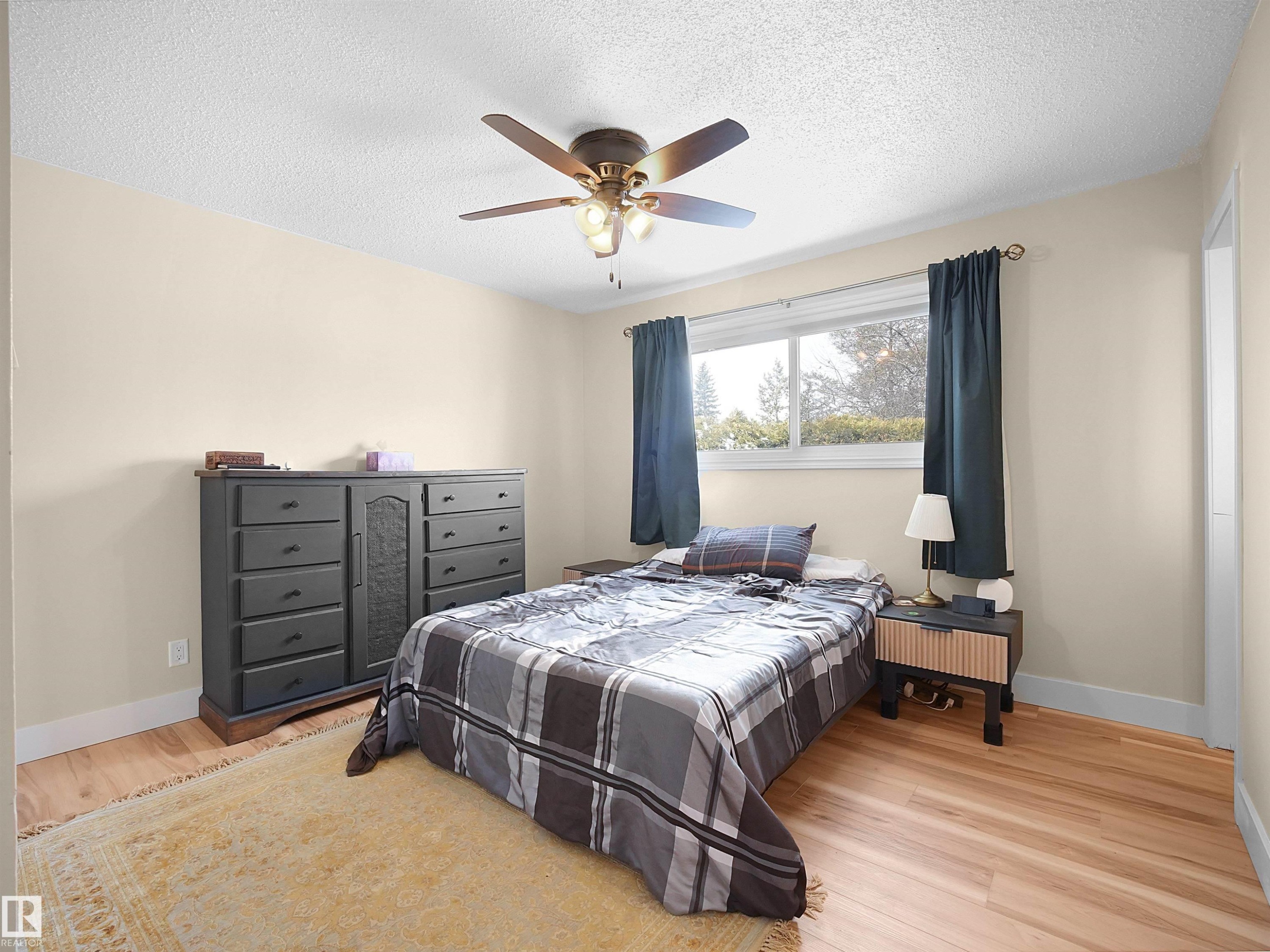 Bedroom featuring wood-finish flooring, a ceiling fan with integrated lighting, and a window with dark drapery - 11044 166 Avenue, Edmonton, AB - Indoor Photo Showing Bedroom