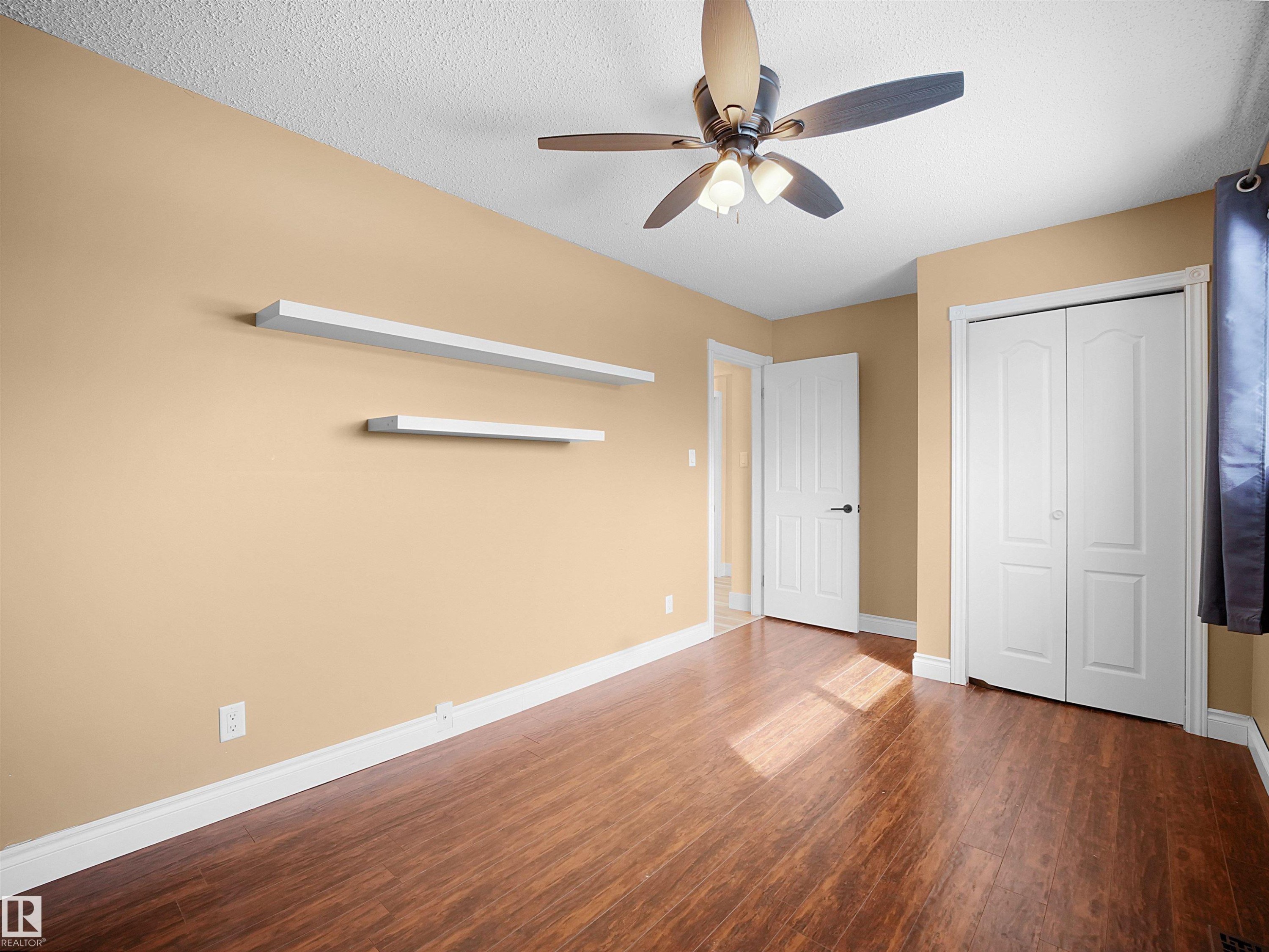 Room featuring wood-finish flooring, a ceiling fan with integrated lighting, and neutral-toned walls - 11044 166 Avenue, Edmonton, AB - Indoor Photo Showing Other Room
