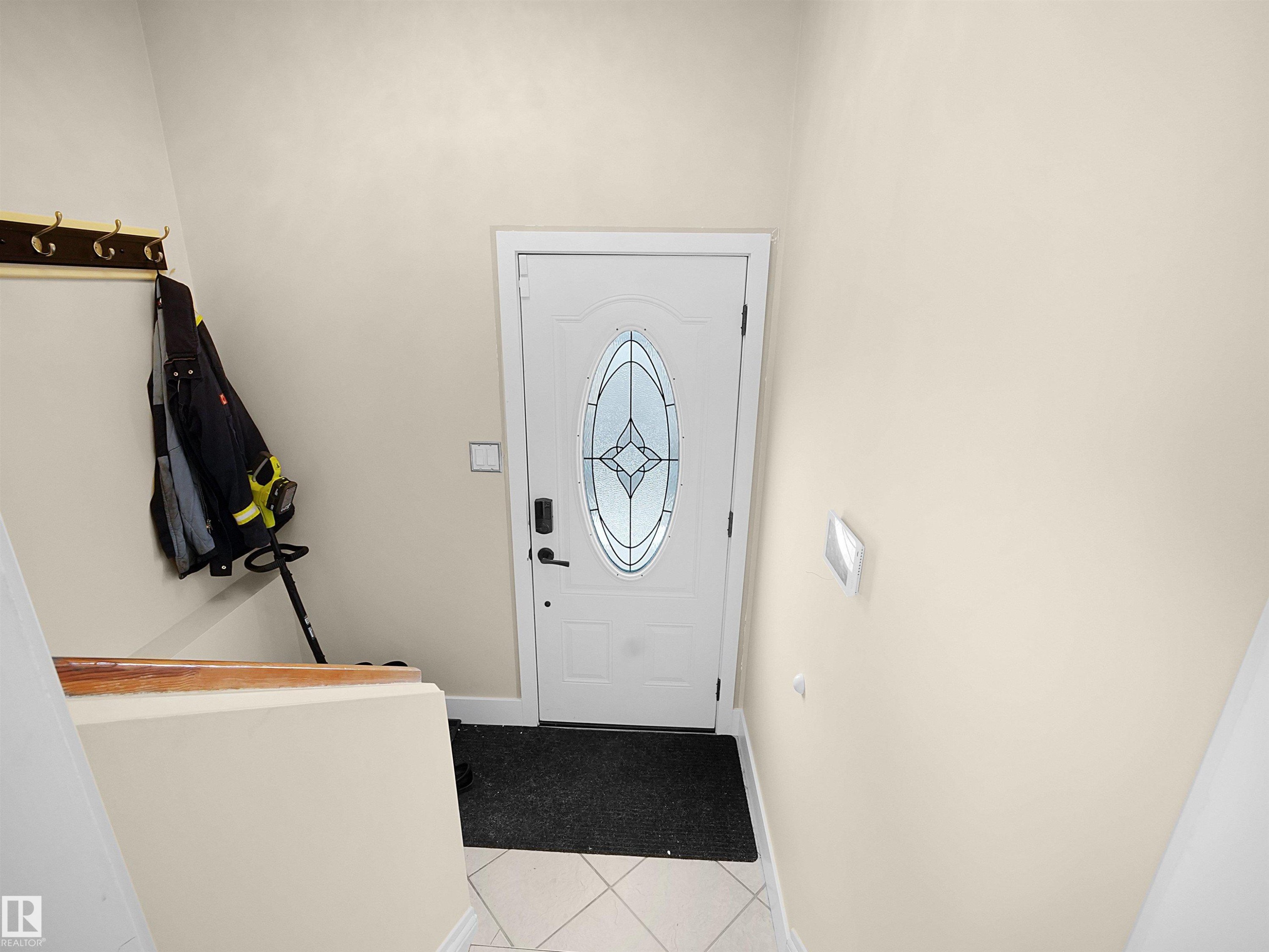 Entryway featuring a white door with decorative glass inserts, square tile flooring, and light-toned walls - 11044 166 Avenue, Edmonton, AB - Indoor