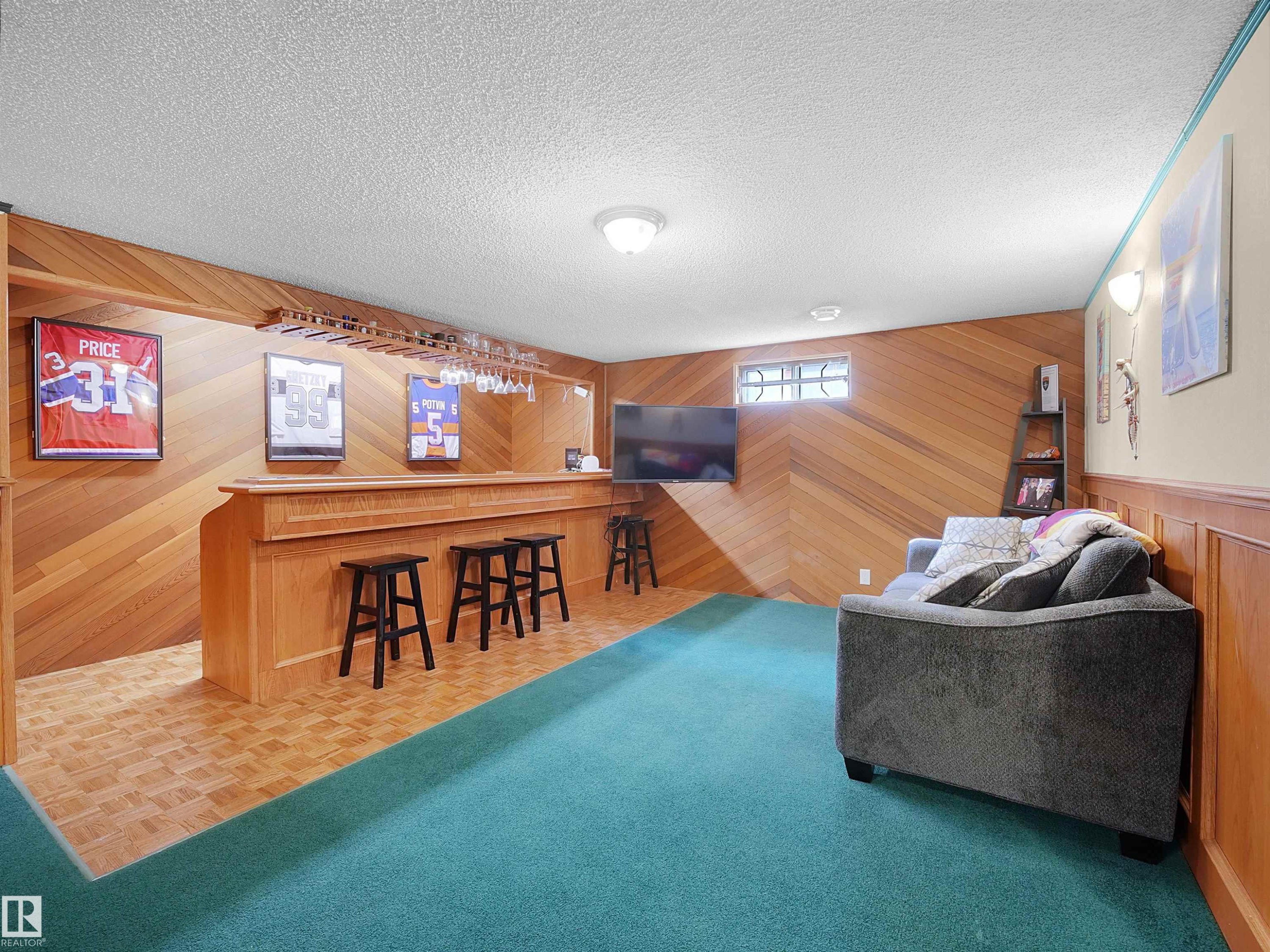 Recreation room featuring a built-in bar, wood-finish wall paneling, and a distinct flooring change - 11044 166 Avenue, Edmonton, AB - Indoor Photo Showing Other Room