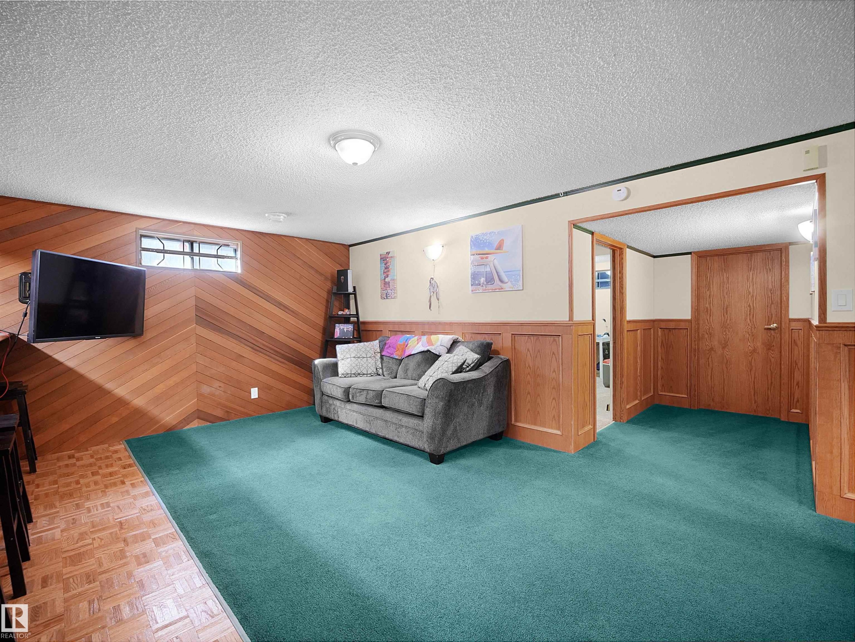 Finished basement room featuring wood paneling, wood-finish flooring, and a window - 11044 166 Avenue, Edmonton, AB - Indoor