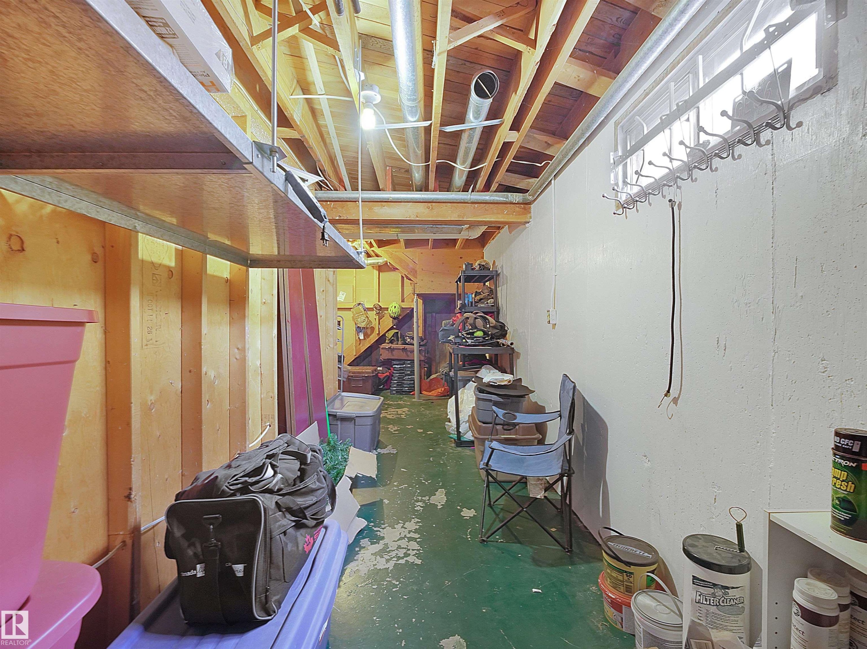 Unfinished basement space featuring exposed wood joists, a fluorescent lighting fixture, and a window with a mounted coat rack - 11044 166 Avenue, Edmonton, AB - Indoor Photo Showing Other Room