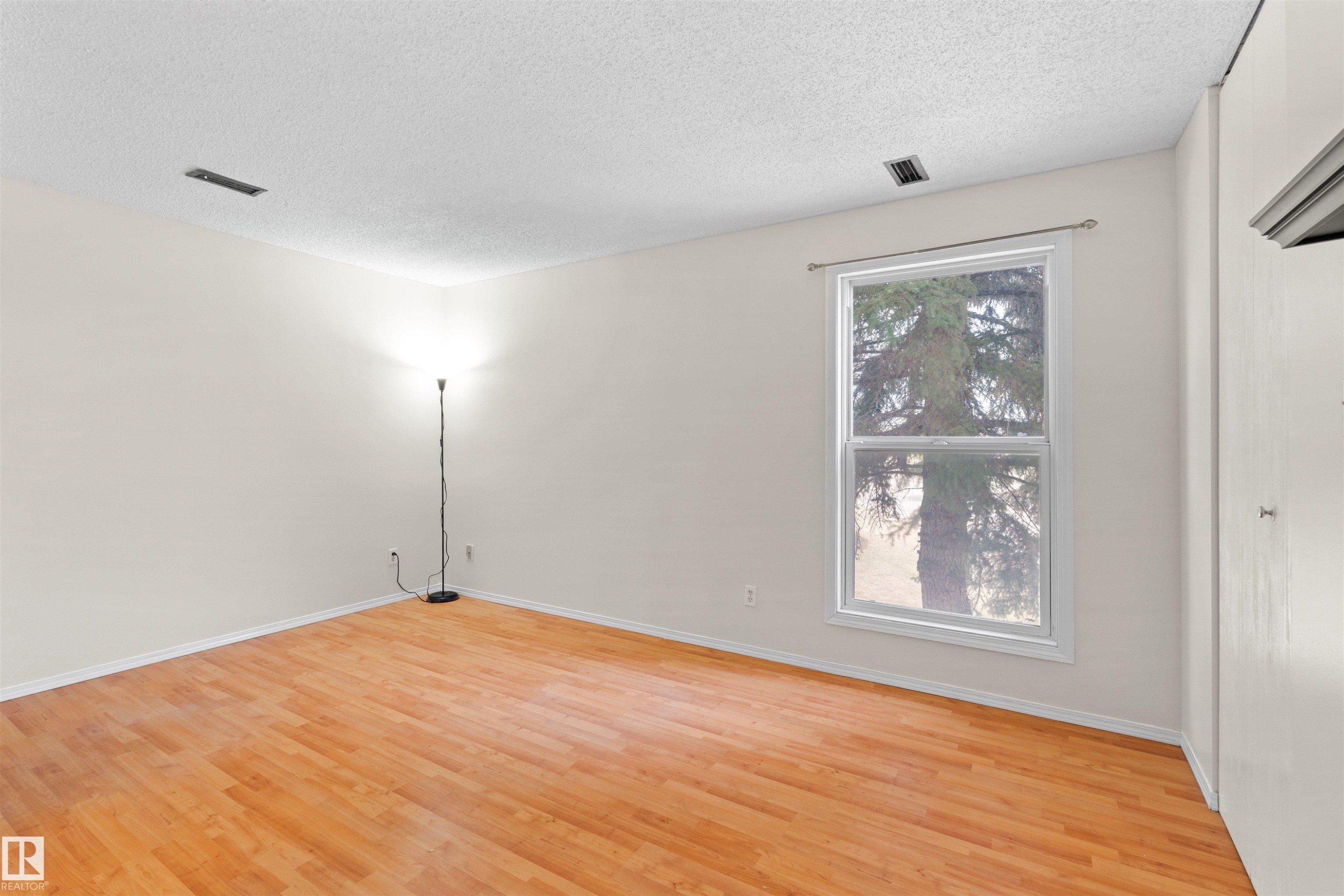 Hardwood-style flooring throughout this room, featuring a bright window with exterior tree scenery - 1116 Saddleback Road, Edmonton, AB - Indoor Photo Showing Other Room