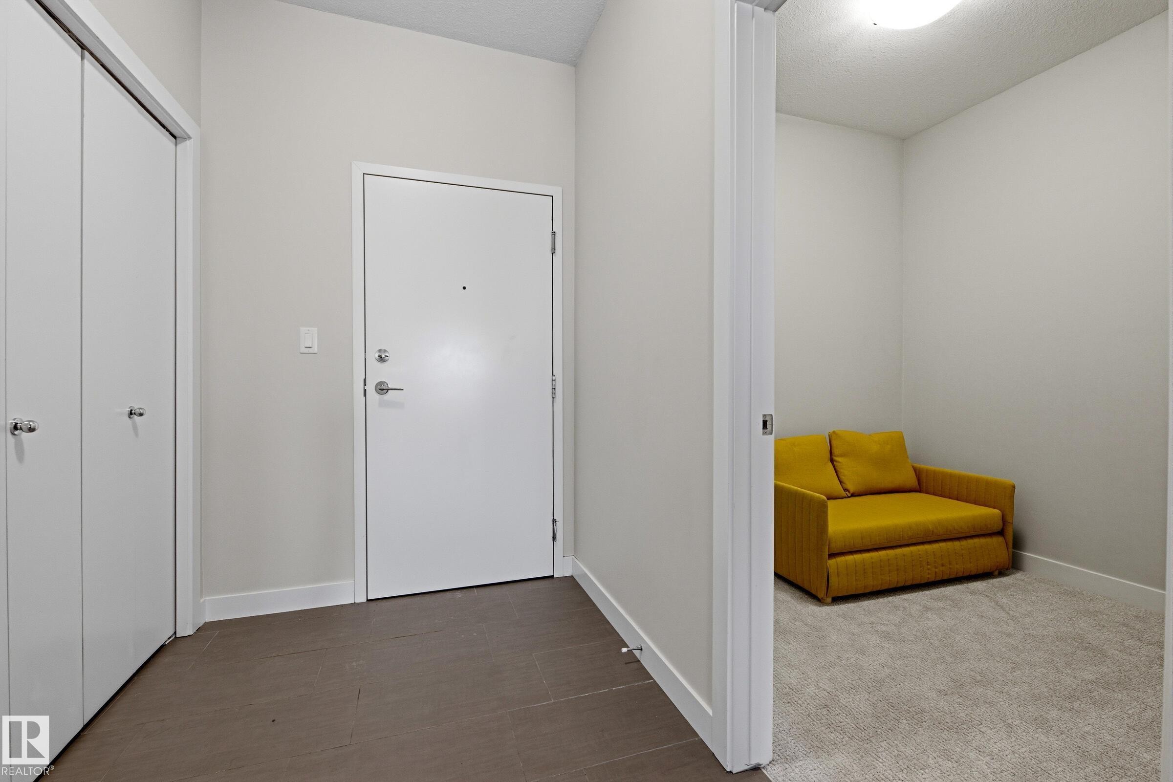 Entryway featuring a solid core door with chrome hardware, dual white bi-fold closet doors, and large format tile flooring - 403 10418 81 Avenue, Edmonton, AB - Indoor Photo Showing Other Room
