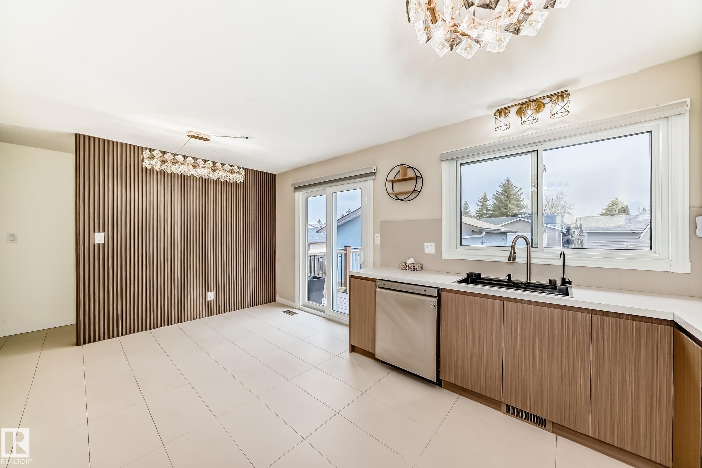 Contemporary kitchen and dining area featuring wood-finish cabinetry, a large window above the sink, stainless steel dishwasher, and a glass sliding door - 2039 48 Street, Edmonton, AB - Indoor Photo Showing Kitchen