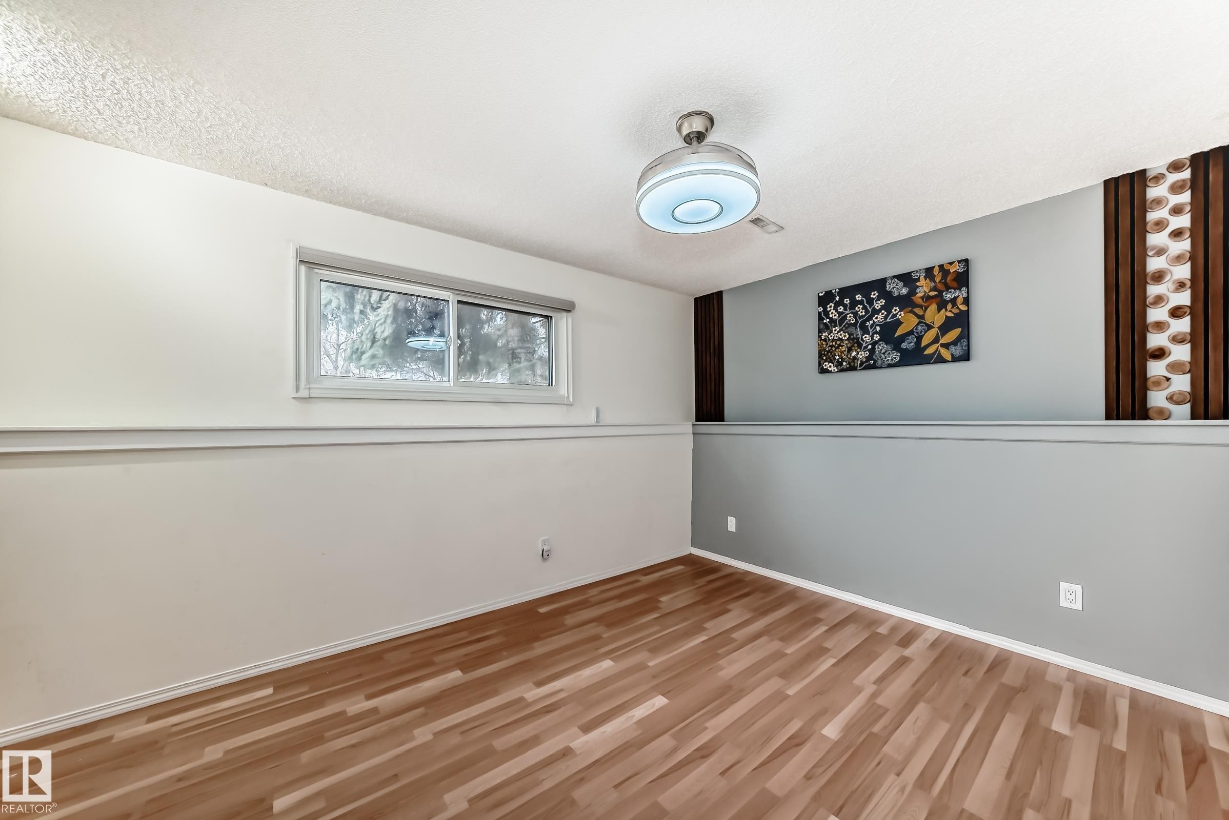 Light wood-finish flooring complements the room's two-tone wall treatment - 2039 48 Street, Edmonton, AB - Indoor Photo Showing Other Room