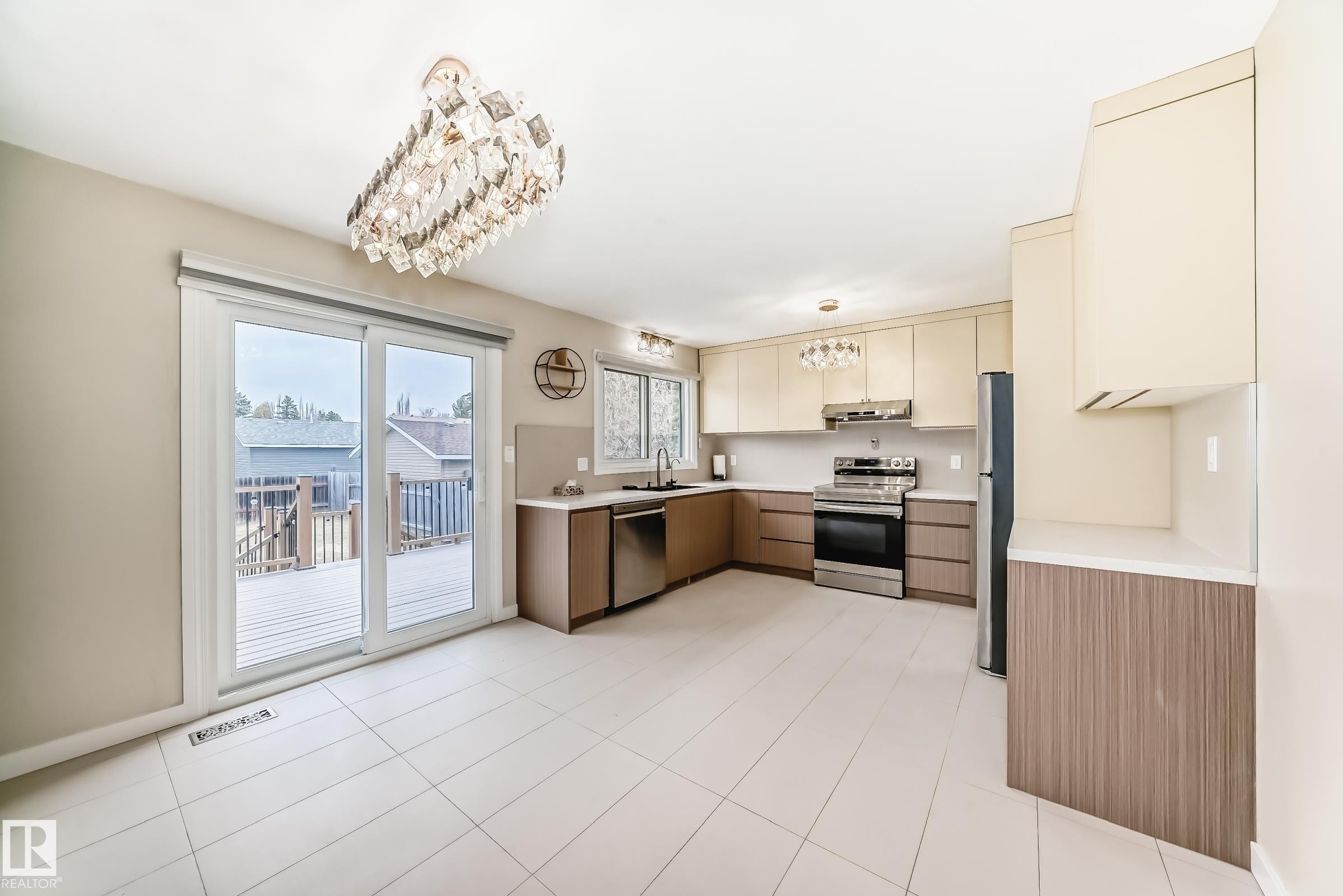 Contemporary kitchen featuring dual-toned cabinetry with light beige uppers and wood-finish lowers, stainless steel appliances, and white countertops - 2039 48 Street, Edmonton, AB - Indoor Photo Showing Kitchen