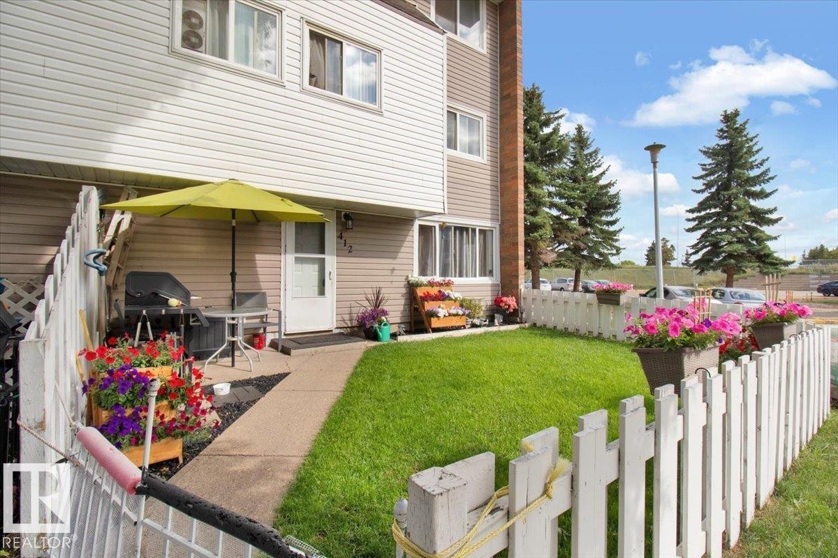 The property features a private fenced lawn area with a paved walkway leading to the entrance - 412 2908 116A Avenue, Edmonton, AB - Outdoor