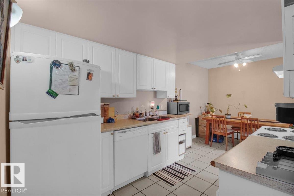 The kitchen features white cabinetry, a refrigerator, and a dishwasher - 412 2908 116A Avenue, Edmonton, AB - Indoor Photo Showing Kitchen With Double Sink