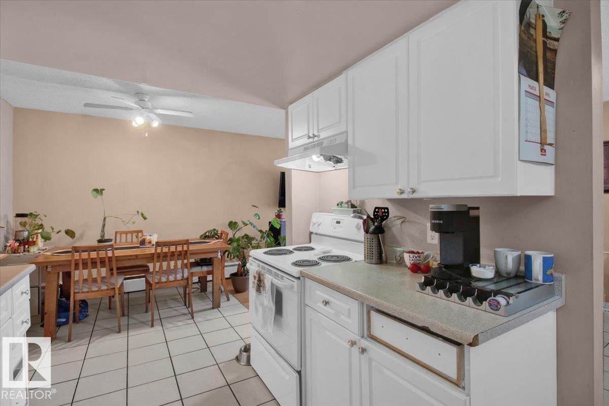 The kitchen features white cabinetry and a white electric range with an overhead microwave - 412 2908 116A Avenue, Edmonton, AB - Indoor Photo Showing Kitchen