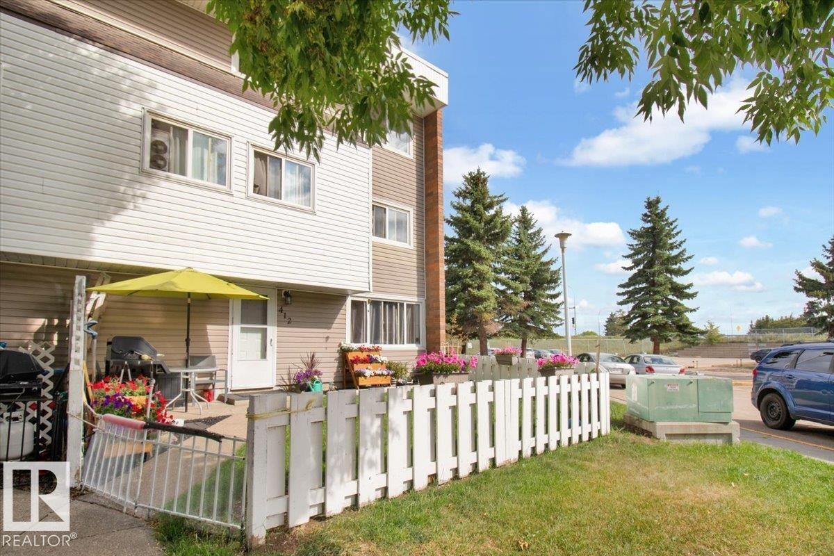 The property features a private patio area, partially enclosed by a white picket fence, offering an outdoor space for relaxation - 412 2908 116A Avenue, Edmonton, AB - Outdoor