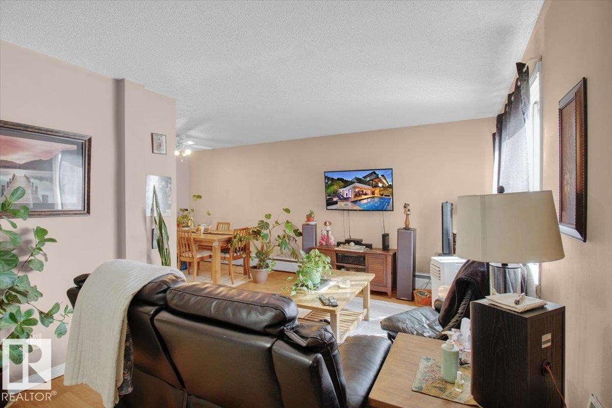 The living area features hardwood flooring, light-colored walls, and a window with dark curtains - 412 2908 116A Avenue, Edmonton, AB - Indoor Photo Showing Other Room