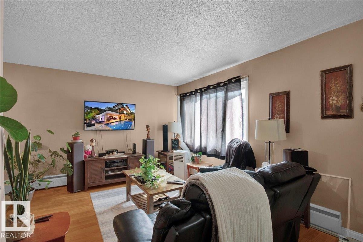 The living area features hardwood floors and a window with dark curtains - 412 2908 116A Avenue, Edmonton, AB - Indoor