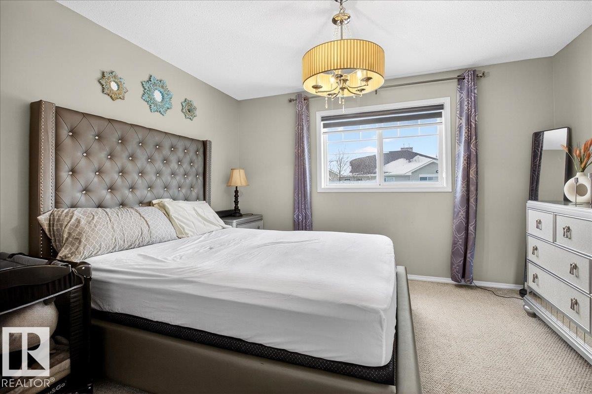 Carpeted bedroom with baseboards and a chandelier - 47 230 Edwards Drive, Edmonton, AB - Indoor Photo Showing Bedroom