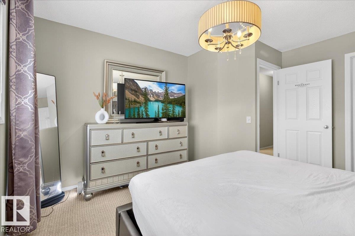 Bedroom with light carpet and a chandelier - 47 230 Edwards Drive, Edmonton, AB - Indoor Photo Showing Bedroom