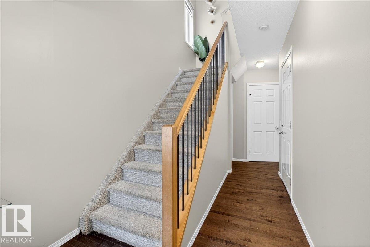 Staircase with baseboards and wood finished floors - 47 230 Edwards Drive, Edmonton, AB - Indoor Photo Showing Other Room