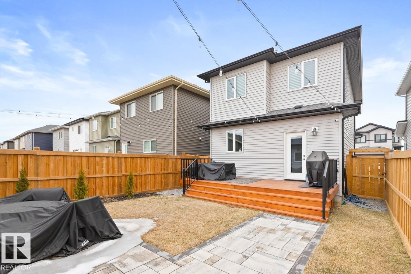 Rear exterior featuring light grey siding and a multi-level wood-finish deck with black railings - 6023 180 Avenue, Edmonton, AB - Outdoor With Deck Patio Veranda With Exterior