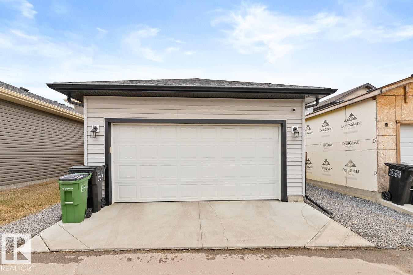 Detached garage with a white panel door, light-colored siding, and black trim - 6023 180 Avenue, Edmonton, AB - Outdoor With Exterior