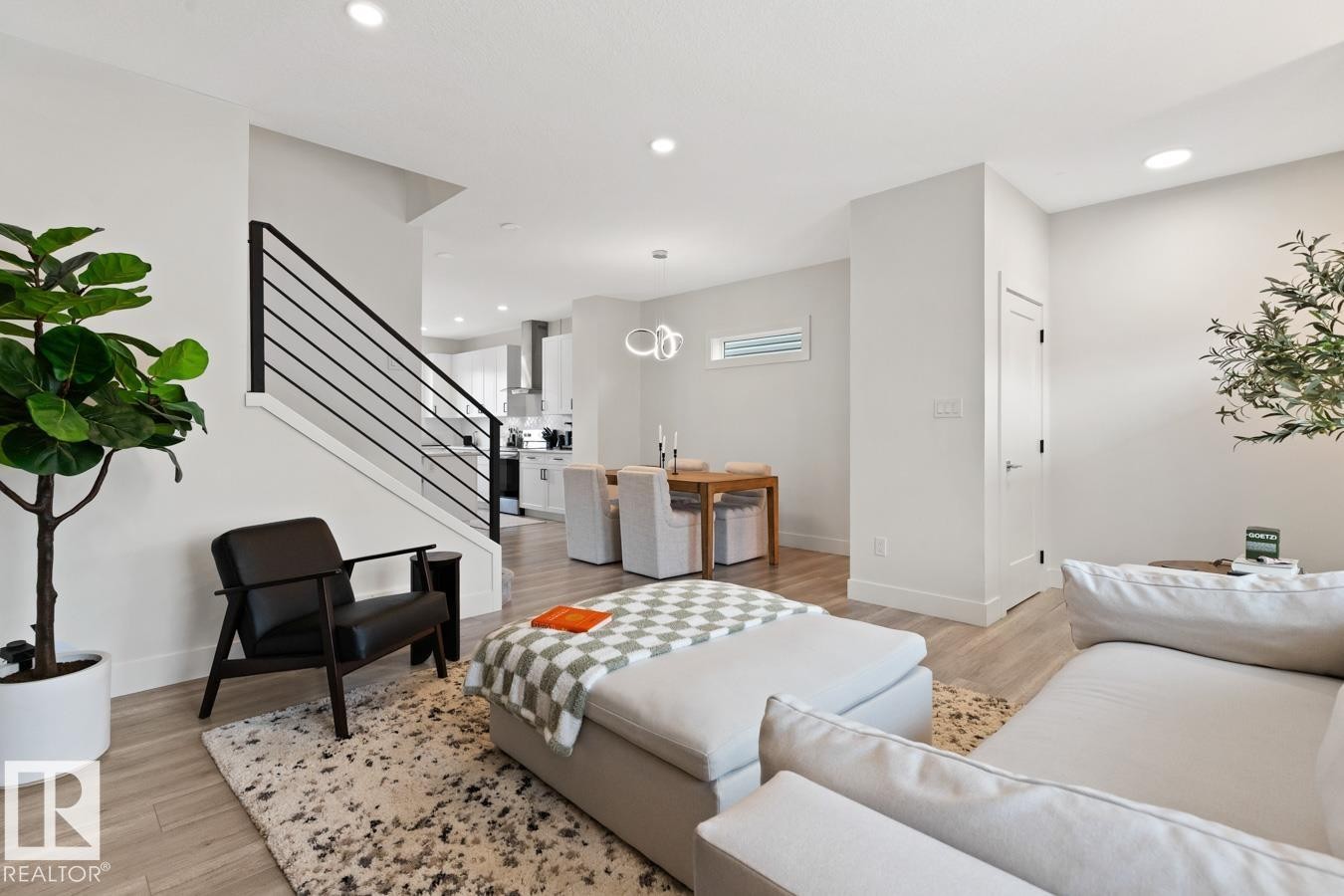 Open-concept living space featuring wood-finish flooring, recessed lighting, and a contemporary black metal staircase railing - 6023 180 Avenue, Edmonton, AB - Indoor Photo Showing Bedroom