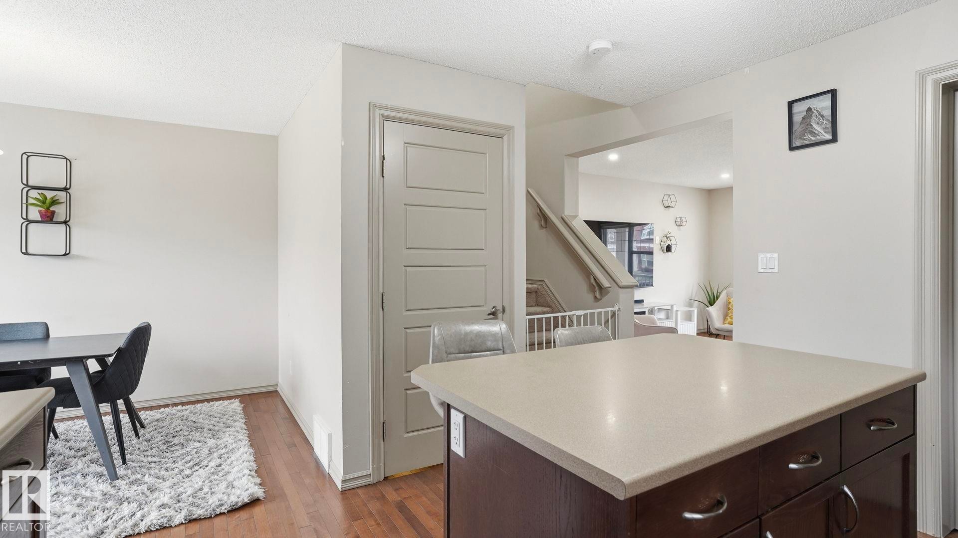 Kitchen island with light-toned countertop, contrasting dark wood cabinetry, and chrome hardware - 8210 180 Avenue Nw, Edmonton, AB - Indoor