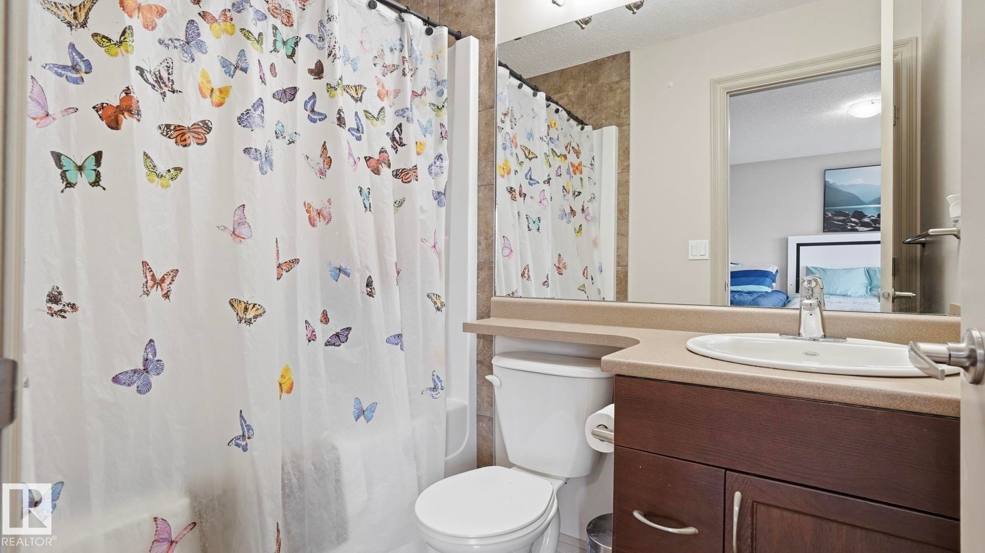 Bathroom featuring a single vanity with dark wood-finish cabinetry, a white basin, and a light-toned countertop - 8210 180 Avenue Nw, Edmonton, AB - Indoor Photo Showing Bathroom