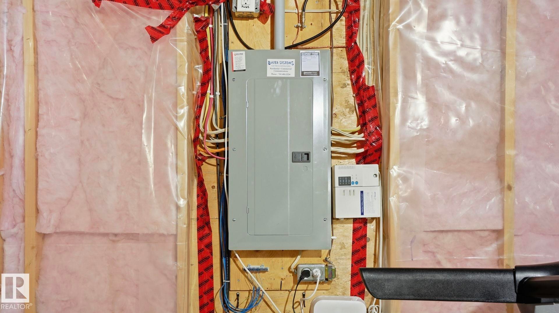 Electrical panel with exposed wiring, wood framing, and pink insulation with vapor barrier - 8210 180 Avenue Nw, Edmonton, AB - Indoor Photo Showing Basement