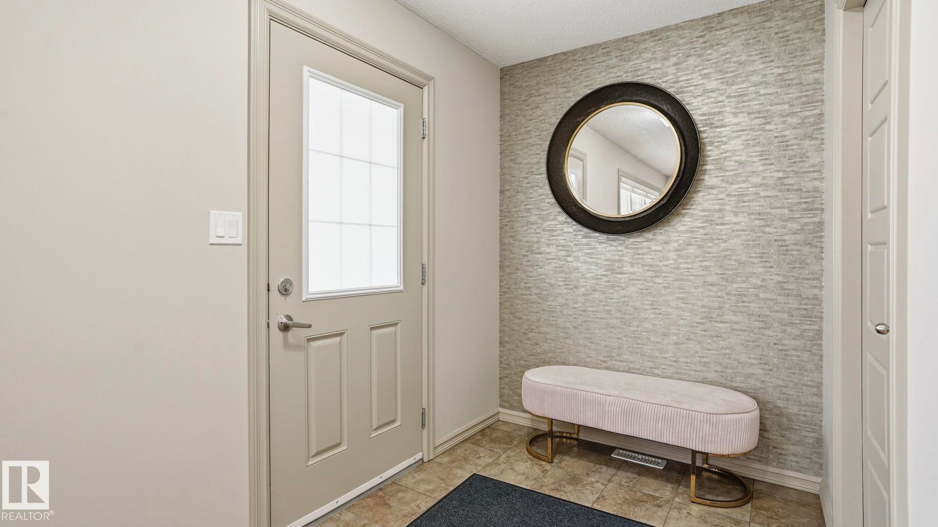 Entryway featuring a panel door with frosted glass insert, textured accent wall, and ceramic tile flooring - 8210 180 Avenue Nw, Edmonton, AB - Indoor Photo Showing Other Room