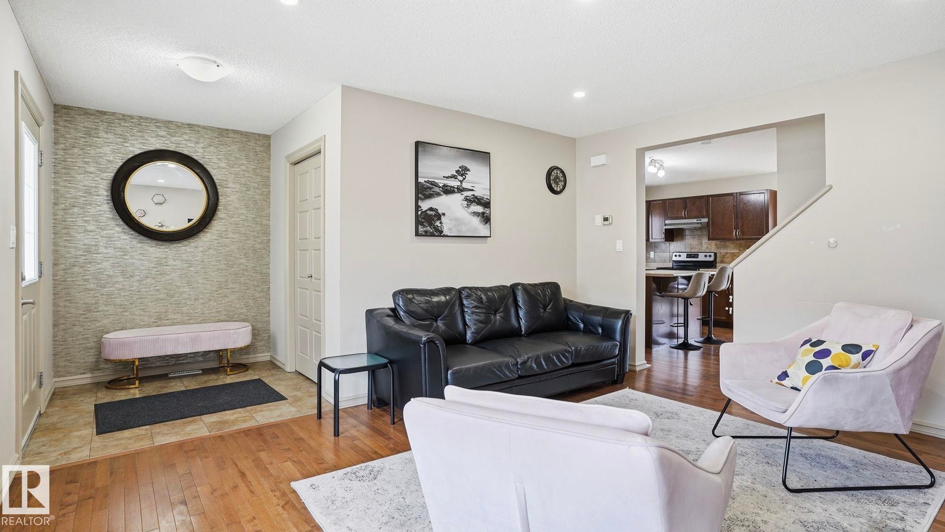 Entryway featuring a textured accent wall, round mirror, and tile flooring - 8210 180 Avenue Nw, Edmonton, AB - Indoor Photo Showing Living Room