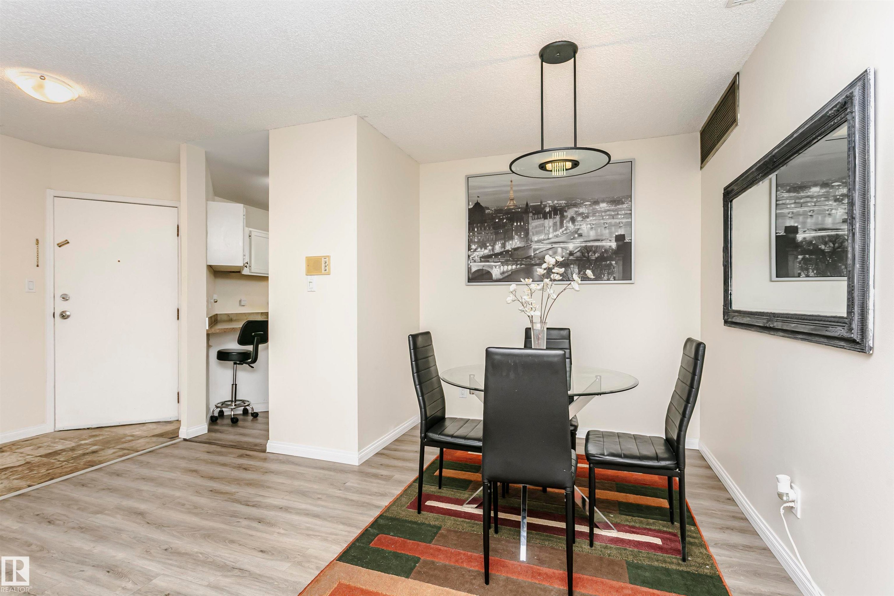 Spacious dining area featuring wood-finish flooring, a contemporary chandelier, light-toned walls, and white baseboards - #303 10026 112 Street Nw, Edmonton, AB - Indoor Photo Showing Dining Room