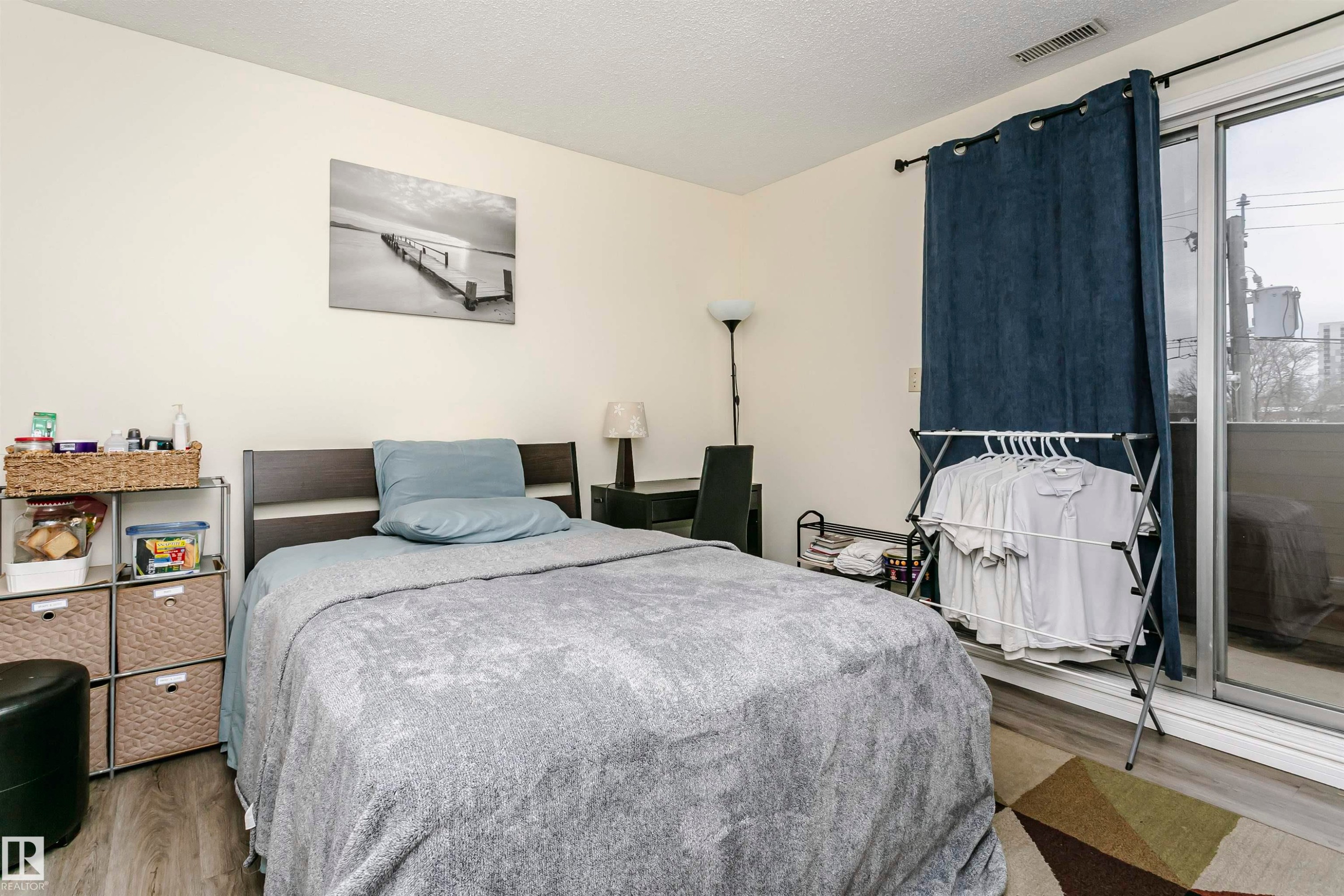 Spacious room featuring wood-finish flooring, a contemporary dark wood headboard, and light-toned walls - #303 10026 112 Street Nw, Edmonton, AB - Indoor Photo Showing Bedroom