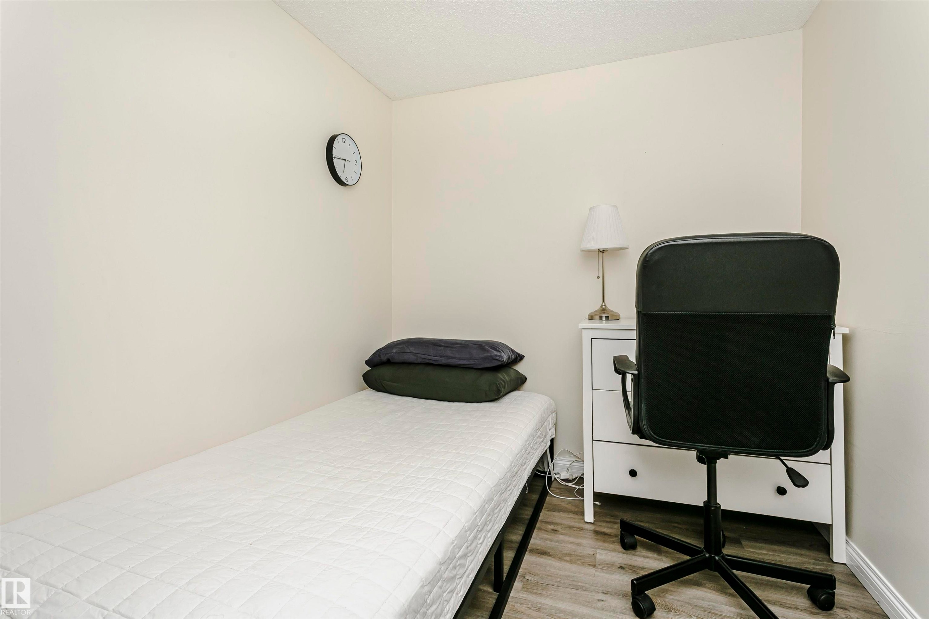 Neutral wall paint and wood-finish flooring highlight this space - #303 10026 112 Street Nw, Edmonton, AB - Indoor Photo Showing Bedroom