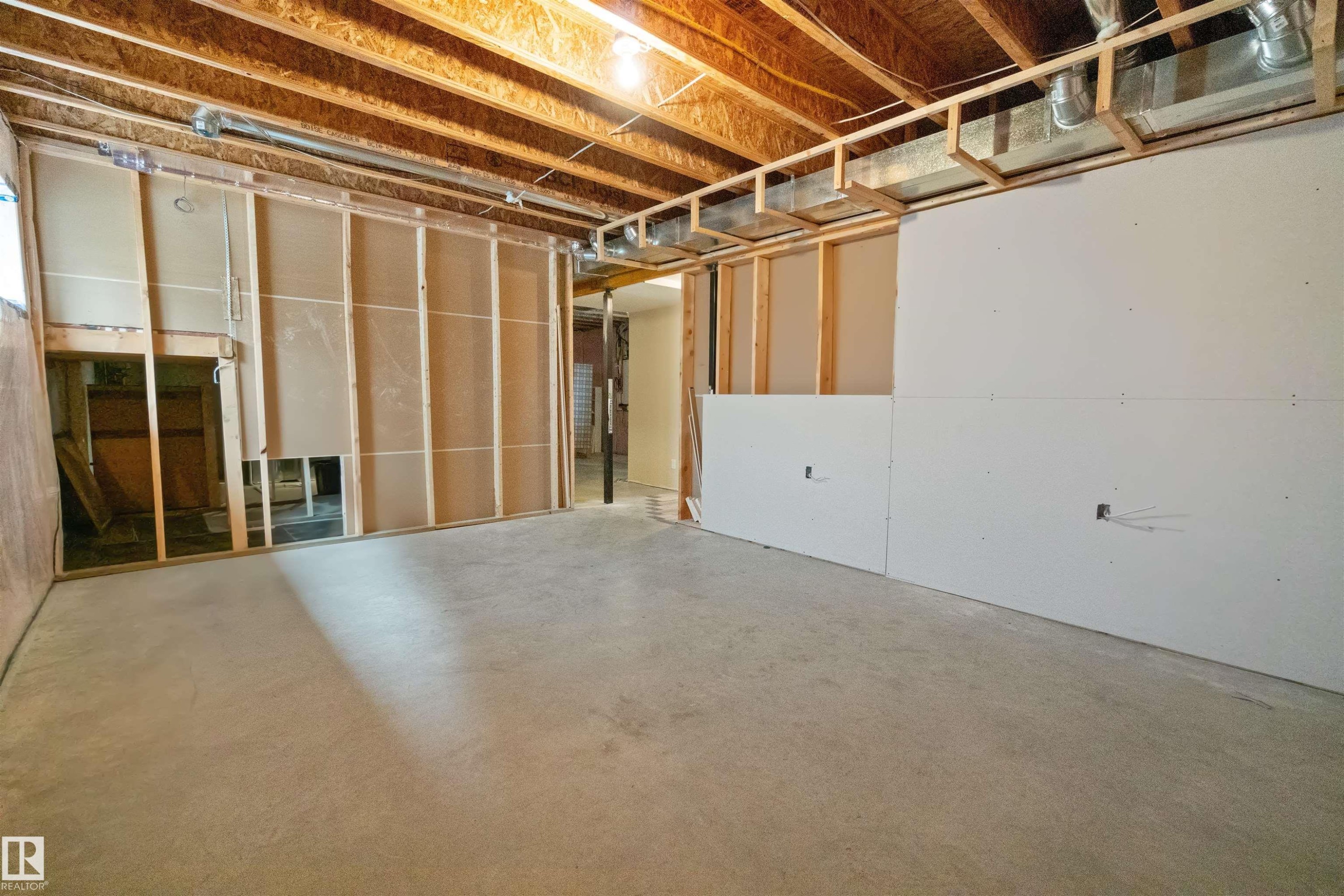 Unfinished basement space featuring exposed wood joists, concrete flooring, and partial drywall installation - 97 Astoria Point(E), Devon, AB