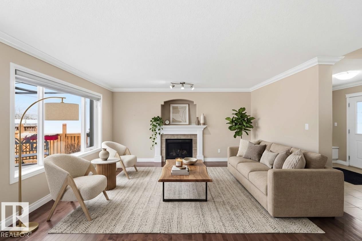 Spacious living area featuring wood-finish flooring, a white trim package, and a decorative fireplace with a mantel - 16412 60 Street, Edmonton, AB - Indoor Photo Showing Living Room With Fireplace
